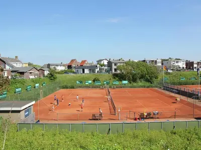 a group of people playing tennis on a tennis court at Holiday Home Egmond near Beach in Egmond aan Zee