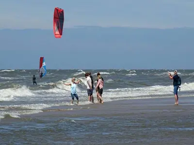 a group of people on the beach flying a kite at Holiday Home Egmond near Beach in Egmond aan Zee