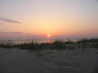 a sunset on a beach with the sun in the distance at Holiday Home Egmond near Beach in Egmond aan Zee