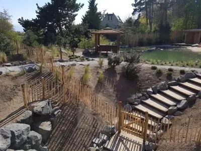 a garden with a pond and a wooden fence at Holiday Home with bubble bath in Noordwijk in Noordwijk