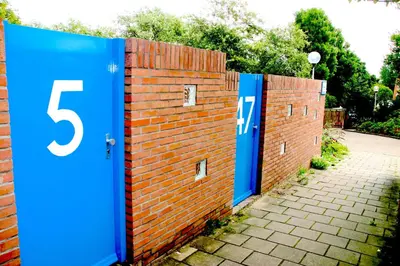 a brick fence with three blue doors on it at Reumann Holiday Apartments De Schelp 47 in Zandvoort