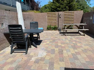 a patio with two chairs and a table and a bench at Reumann Holiday Apartments De Schelp 47 in Zandvoort