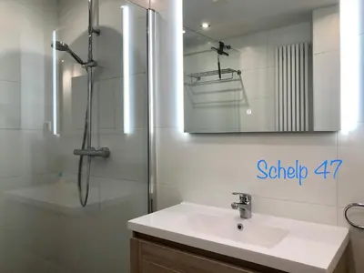 a bathroom with a sink and a shower with a mirror at Reumann Holiday Apartments De Schelp 47 in Zandvoort