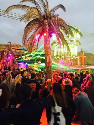 a crowd of people at a party with a palm tree at Reumann Holiday Apartments De Schelp 47 in Zandvoort