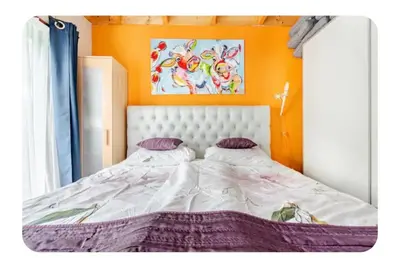 a bed in a room with an orange wall at Kitty's Place Warmond in Warmond