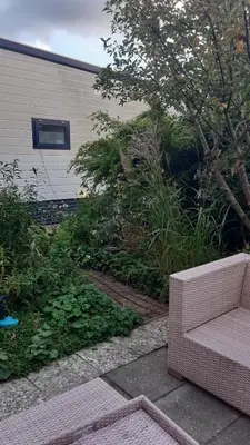 a wicker couch sitting on a patio in a yard at Kitty's Place Warmond in Warmond