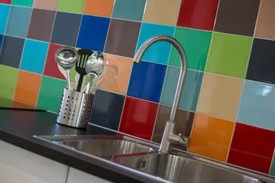 a sink in a kitchen with a colorful tiled wall at Ghoyhuys in Leiderdorp