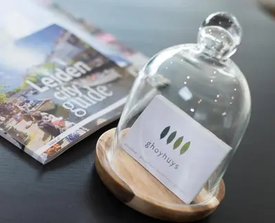 a glass bottle sitting on a table with a magazine at Ghoyhuys in Leiderdorp