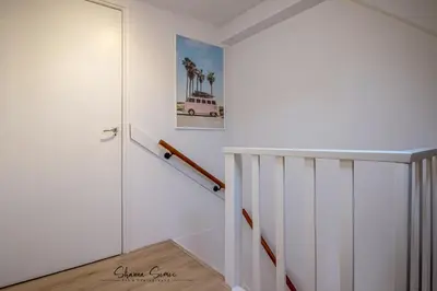 a hallway with white walls and a stair case at Carpe Diem Egmond aan Zee by Urban Home Stay in Egmond aan Zee