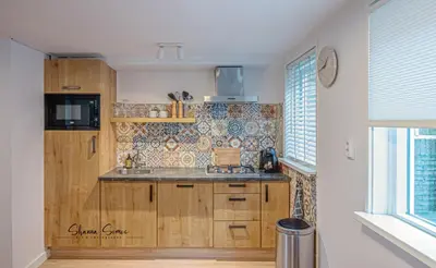 a kitchen with wooden cabinets and a counter top at Carpe Diem Egmond aan Zee by Urban Home Stay in Egmond aan Zee