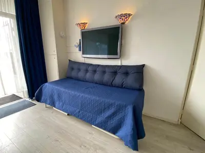 a room with a bed with a tv on the wall at Reumann Holiday Apartments De Schelp 5 in Zandvoort