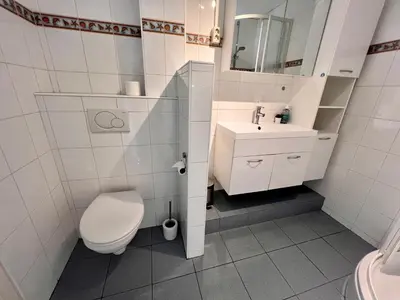 a white bathroom with a toilet and a sink at Reumann Holiday Apartments De Schelp 5 in Zandvoort