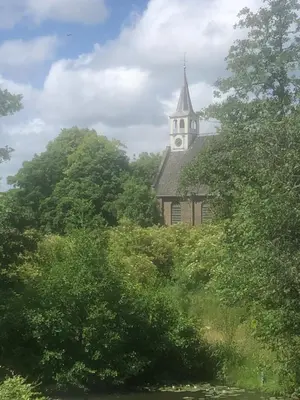 a church with a clock tower in the middle of trees at Luxe Room Canal Sight in Amsterdam
