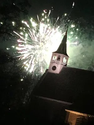a church steeple with fireworks exploding in the sky at Luxe Room Canal Sight in Amsterdam
