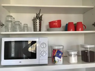 a white microwave on a shelf with bowls and plates at Luxe Room Canal Sight in Amsterdam