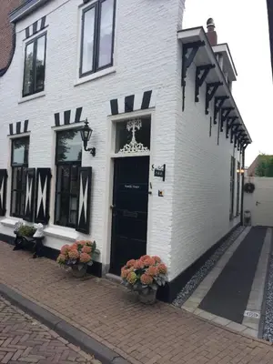 a white building with a black door and flowers at B&B 'De Bedstee' in Rijnsburg