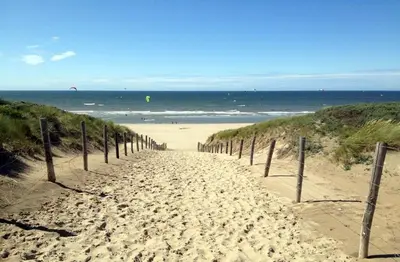 a sandy path leading to a beach with the ocean at B&B 'De Bedstee' in Rijnsburg