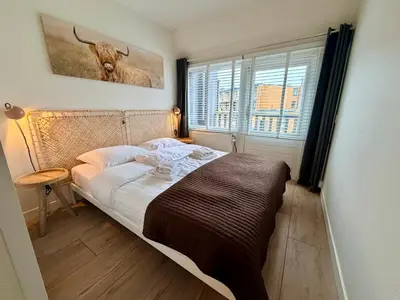 a bedroom with a bed with a bull painting on the wall at SummerTime Bergen aan Zee in Bergen aan Zee