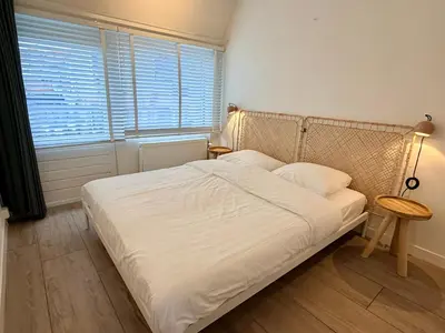 a bedroom with a white bed with a lamp and a window at SummerTime Bergen aan Zee in Bergen aan Zee