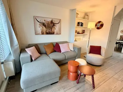 a living room with a couch and a bull painting on the wall at SummerTime Bergen aan Zee in Bergen aan Zee