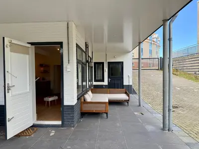 a building with a patio with a couch and a table at SummerTime Bergen aan Zee in Bergen aan Zee
