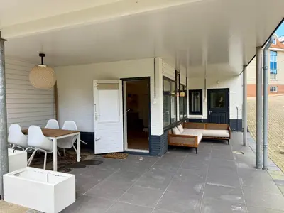 a patio with a table and chairs and a table at SummerTime Bergen aan Zee in Bergen aan Zee