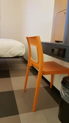 a chair in a room with a bed and a desk at easyHotel Amsterdam Arena Boulevard in Amsterdam