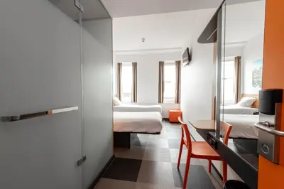 a room with two beds and a table and a mirror at easyHotel Amsterdam Arena Boulevard in Amsterdam