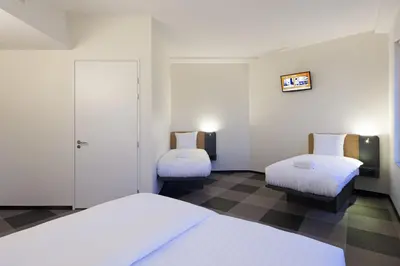 a room with two beds and a chair in it at easyHotel Amsterdam Arena Boulevard in Amsterdam