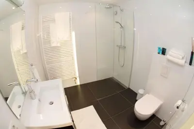 a white bathroom with a shower and a toilet at Marbles Inn in Amsterdam