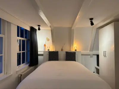 a bedroom with a white bed and two windows at Nine Streets Inn in Amsterdam
