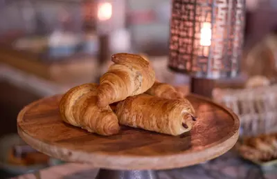 three croissants on a wooden plate on a table at The July - Twenty Eight in Amsterdam