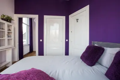 a bedroom with purple walls and a white bed with purple pillows at B&B Slapen bij de burgemeester in Sint Pancras