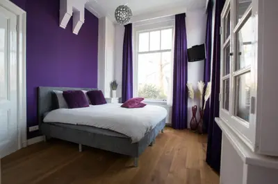 a bedroom with purple walls and a bed with purple pillows at B&B Slapen bij de burgemeester in Sint Pancras