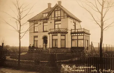 an old photo of a house with two people standing in front at B&B Slapen bij de burgemeester in Sint Pancras