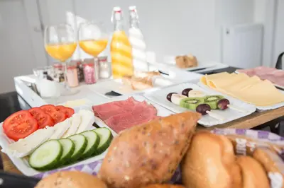 a table with plates of food and glasses of wine at B&B Slapen bij de burgemeester in Sint Pancras