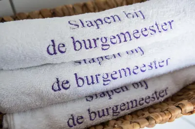 three towels with handwriting on them in a basket at B&B Slapen bij de burgemeester in Sint Pancras