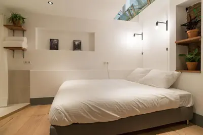 a bedroom with a large bed with white sheets at Saint Claire Studio in Amsterdam