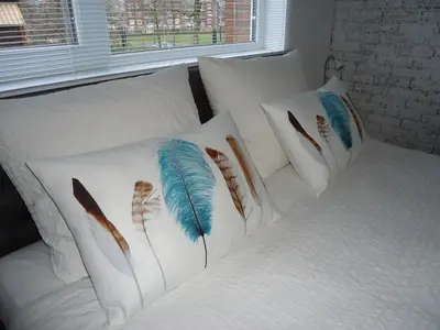 a white bed with four pillows with feathers on it at B&B Sloterpark in Amsterdam