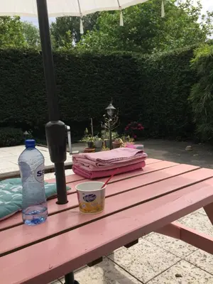 a picnic table with an umbrella and a bottle of water at B&B Sloterpark in Amsterdam