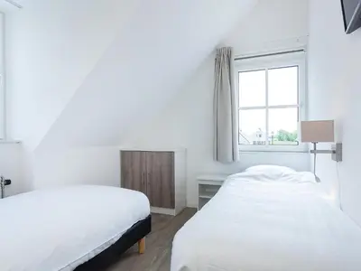 two beds in a white room with a window at Holiday Home Alk 8-1 by Interhome in Noordwijkerhout