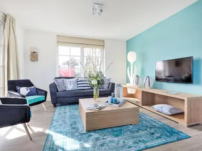a living room with a couch and a tv at Holiday Home Tapuit 6-2 by Interhome in Noordwijk