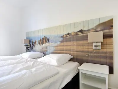 a bedroom with two beds and a painting on the wall at Holiday Home Tapuit 8-1 by Interhome in Noordwijk