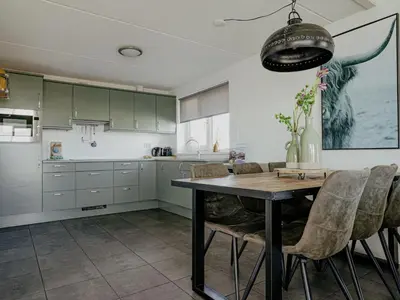 a kitchen with green cabinets and a wooden table at Holiday Home Kraaijennest by Interhome in Uitgeest
