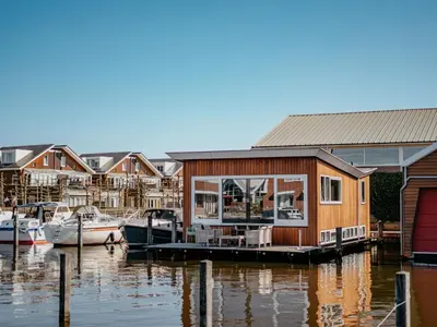 a house on a dock with boats in the water at Holiday Home De Woude by Interhome in Uitgeest