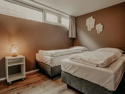 a bedroom with two beds and a table with a lamp at Holiday Home De Woude by Interhome in Uitgeest