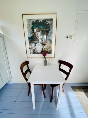 a white table with two chairs and a painting on the wall at Tiny House De Oude Berg in Bergen