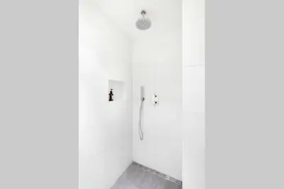 a bathroom with a shower with white walls at Tiny House De Oude Berg in Bergen