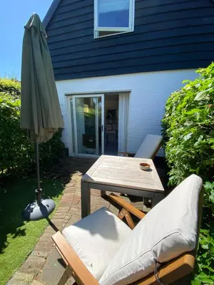 a patio with an umbrella and a table and chairs at Tiny House De Oude Berg in Bergen