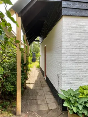 a side of a white building with a walkway at Tiny House De Oude Berg in Bergen